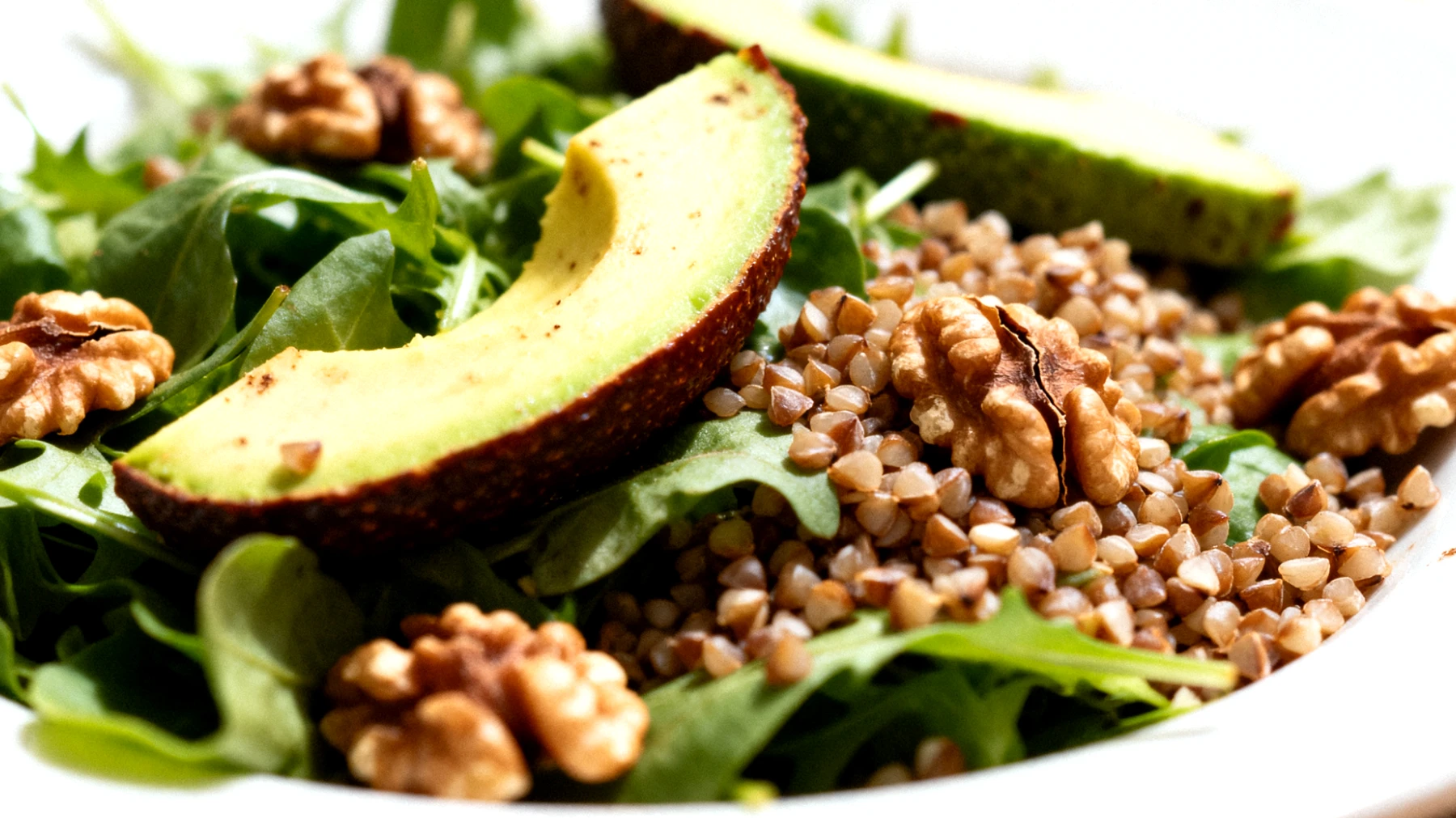 Insalata di grano saraceno con avocado, noci e verdure a foglia verde"